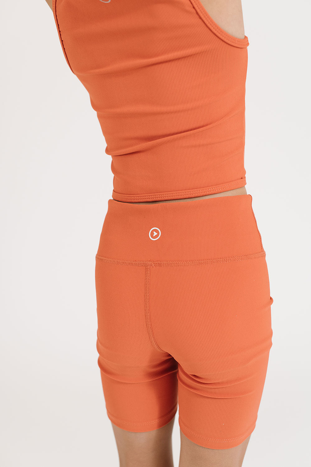 Young girl wearing Everyway kids activewear. Featuring Ribbed Cycle Shorts in Persimmon.