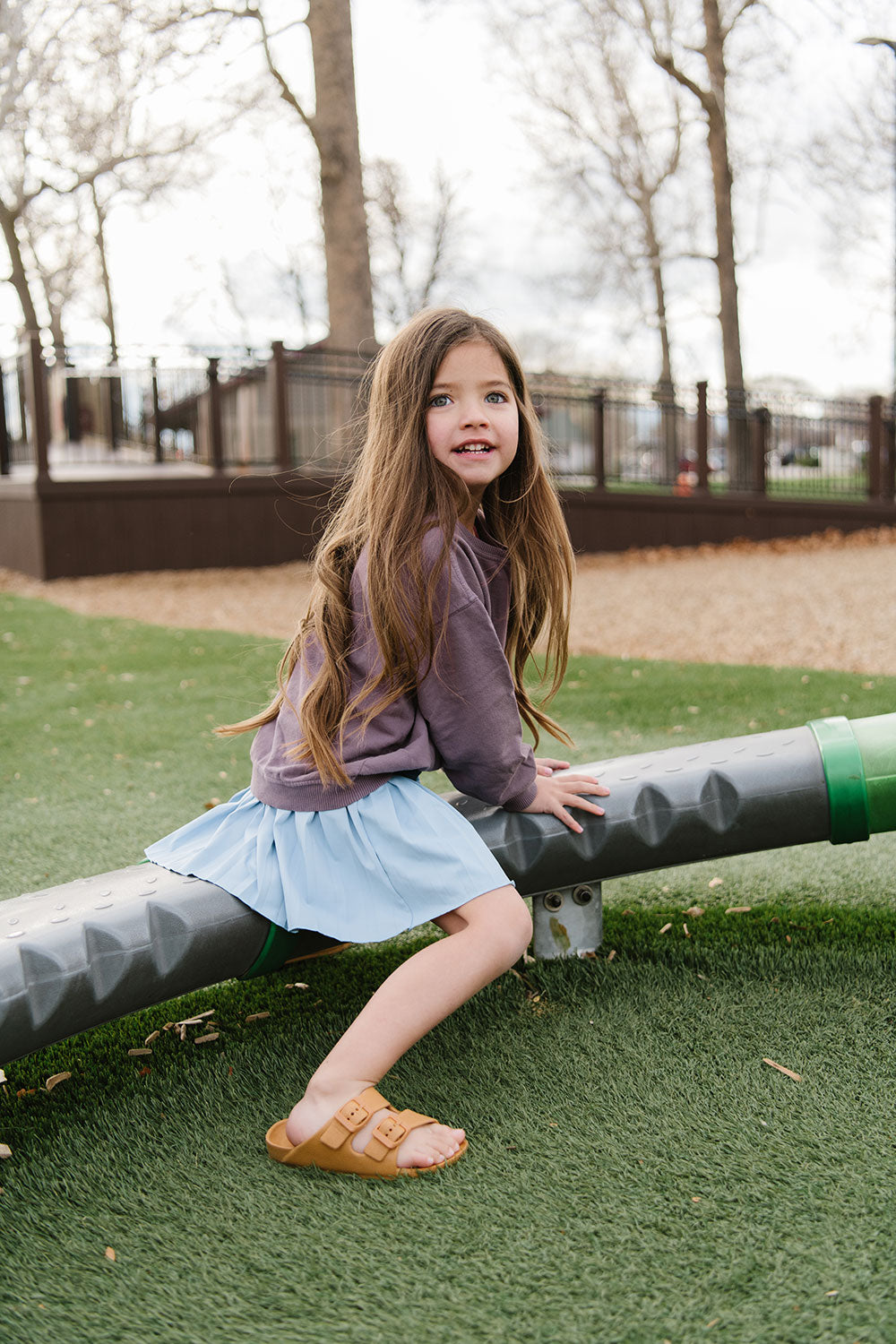 Young girl wearing Everyway kids activewear. Featuring Pleated Court Skort in Ocean.