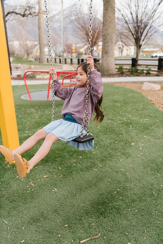 Young girl wearing Everyway kids activewear. Featuring Pleated Court Skort in Ocean.