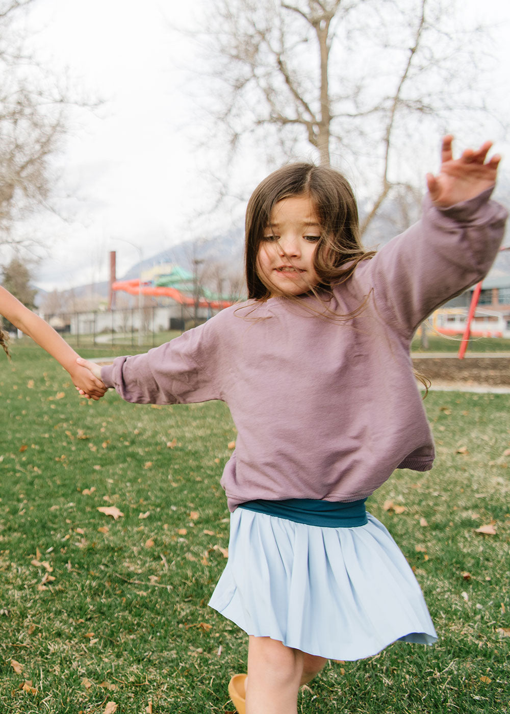 Young girl wearing Everyway kids activewear. Featuring Pleated Court Skort in Ocean.