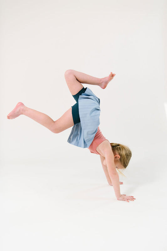 Young girl wearing Everyway kids activewear. Featuring Pleated Court Skort in Ocean.