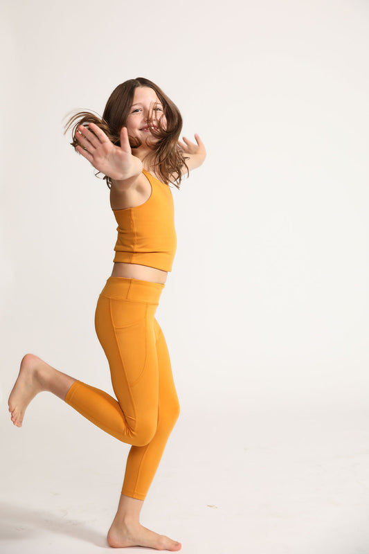 Young girl wearing Everyway kids activewear. Featuring Inca Gold Longline Crop and All Day Leggings.