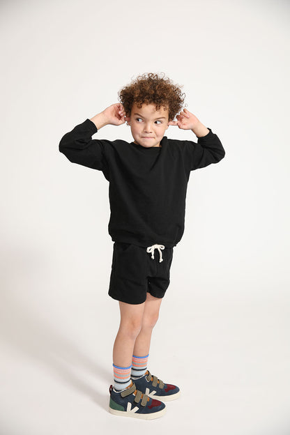 Young boy wearing Everyway kids activewear. Featuring Core Sweat Shorts in Black.