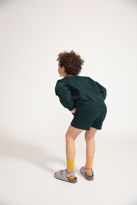 Young boy wearing Everyway kids activewear. Featuring Core Sweat Shorts in Pine.