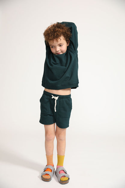 Young boy wearing Everyway kids activewear. Featuring Core Sweat Shorts in Pine.