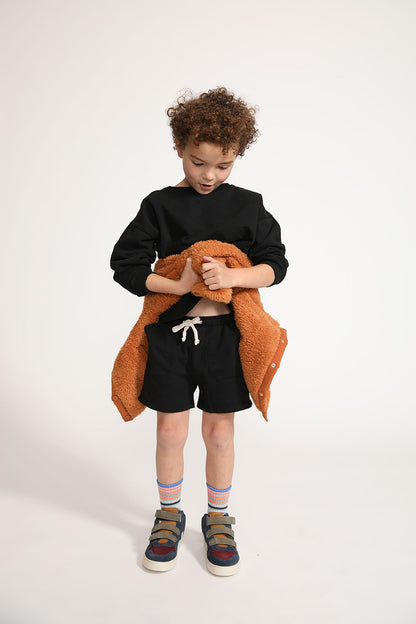 Young boy wearing Everyway kids activewear. Featuring Core Sweat Shorts in Black.