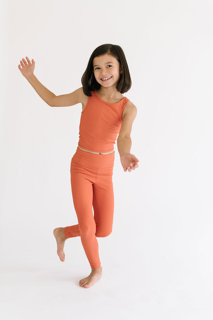 Young girl wearing Everyway kids activewear. Featuring Sporty Ribbed Leggings in Persimmon.