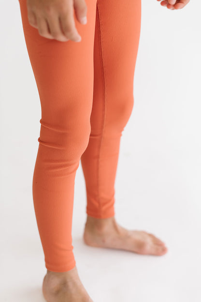 Young girl wearing Everyway kids activewear. Featuring Sporty Ribbed Leggings in Persimmon.