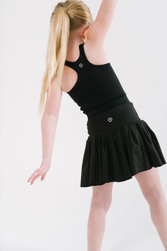 Young girl wearing Everyway kids activewear. Featuring Pleated Court Skort in Black.