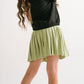 Young girl wearing Everyway kids activewear. Featuring Pleated Court Skort in Lime.