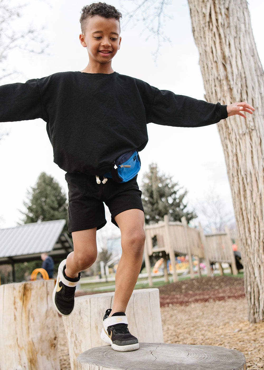 Young boy playing in a park in Everyway activewear. Featuring fanny pack in blue