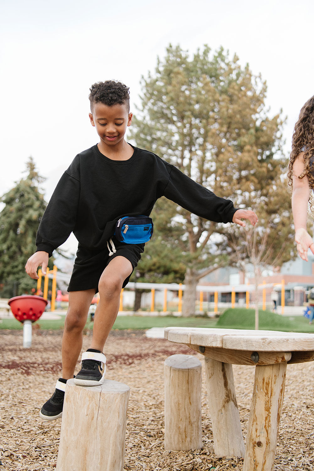 Young boy playing in a park in Everyway activewear. Featuring fanny pack in blue