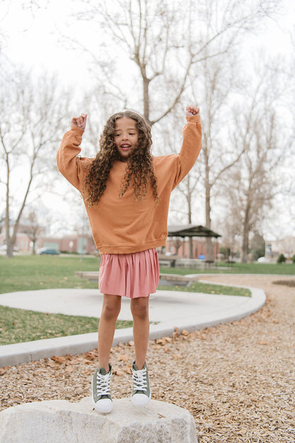 Young girl wearing Everyway kids activewear. Featuring Pleated Court Skort in Rose.