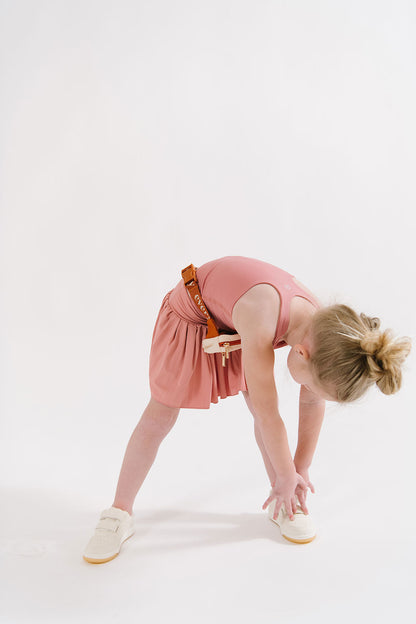 Young girl wearing Everyway kids activewear. Featuring Pleated Court Skort in Rose.